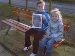 George and Hannah sitting on Charlie's seat holding a photograph of Charlie